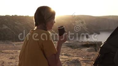 迷人的女孩徒步旅行坐在帐篷附近的背景山和<strong>罪恶</strong>上升。 喝咖啡或茶